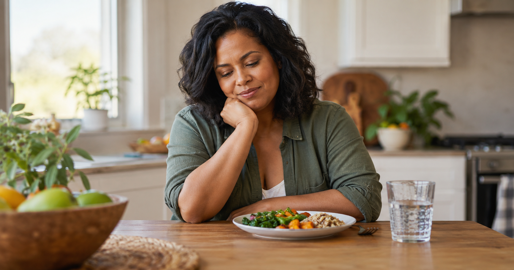 Woman looking thoughtfully at a plate of food, considering foods that may trigger psoriasis flares